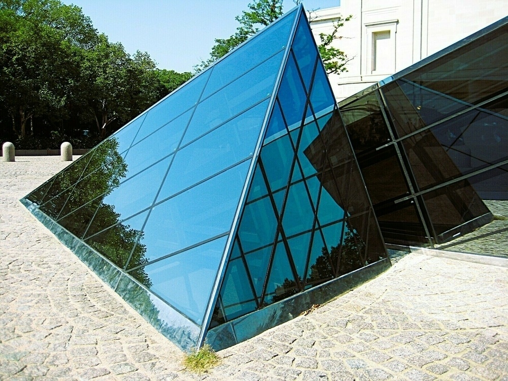 A triangular, mirrored structure among cobblestones.