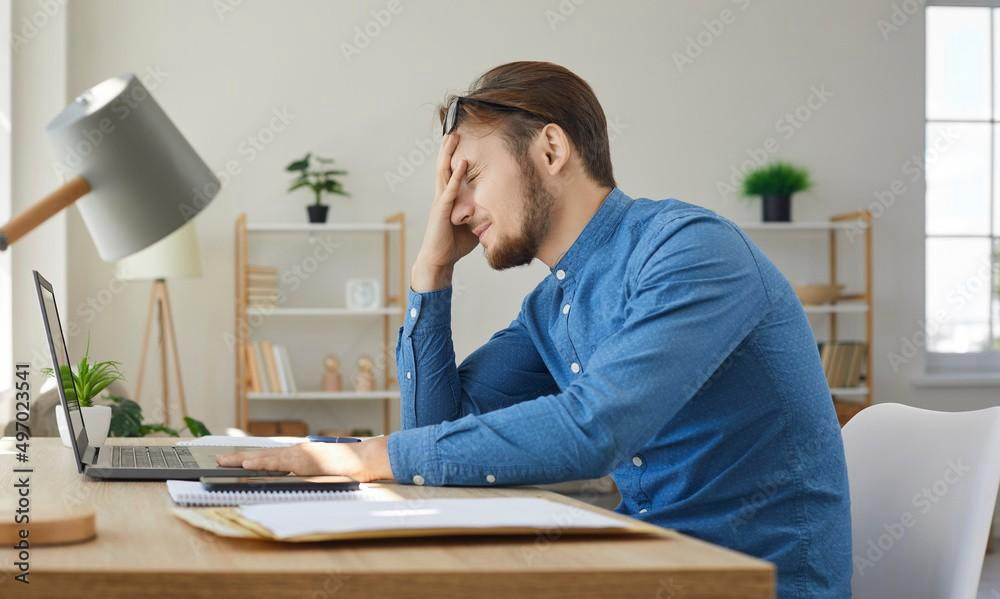 A tired man sitting in front of a computer b