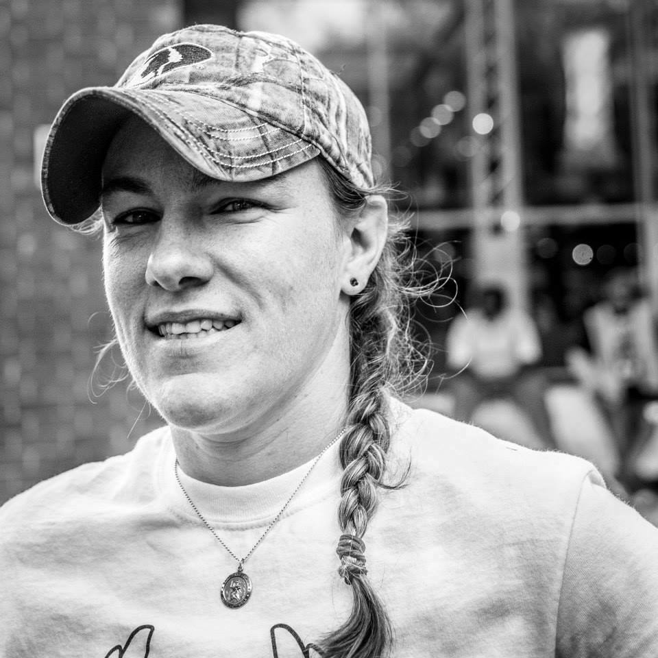 An athletic woman in a baseball hat with her hair in a single braid.