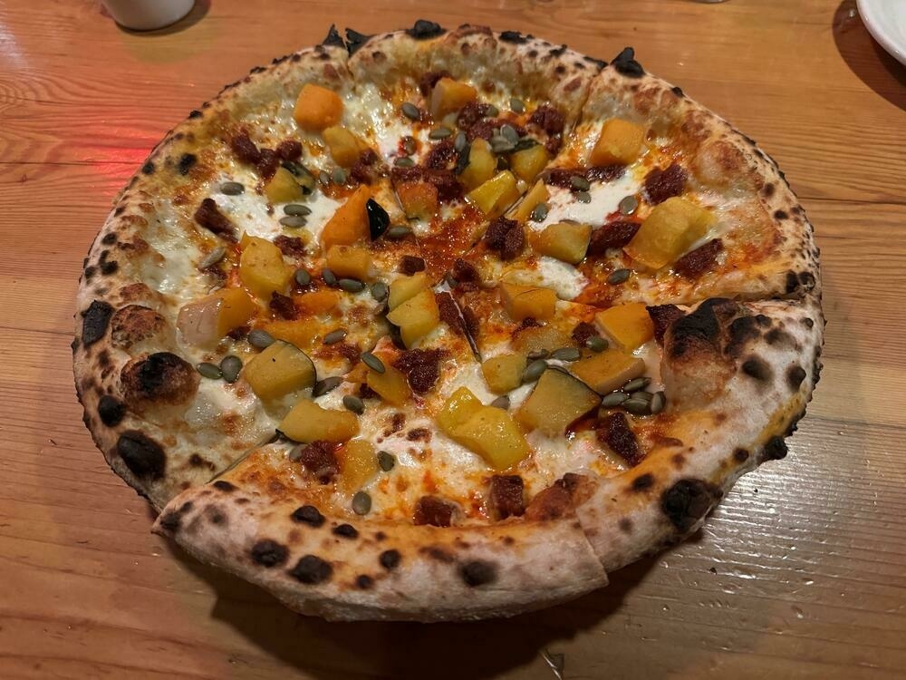 A beautifully charred and speckled neapolitan pizza topped with mozzarella, pepitas, globs of n’duja, and cubes (yes, CUBES) of winter squash.