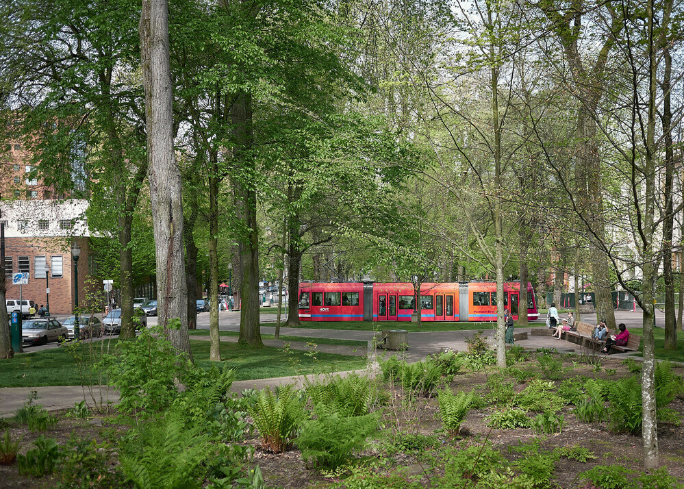 The North-South Portland Streetcar line at Park Avenue and Mill Street in Portland's South Park blocks near Portland State University. People are sitting on park benches reading.