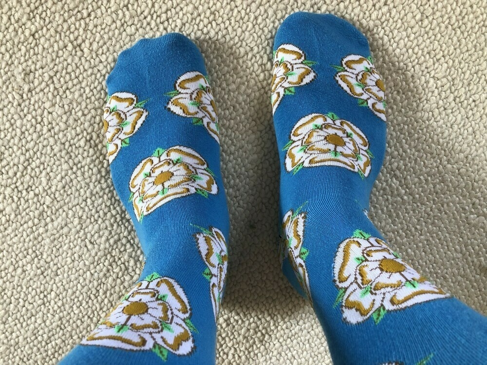 A pair of socks depicting the white Yorkshire rose. 