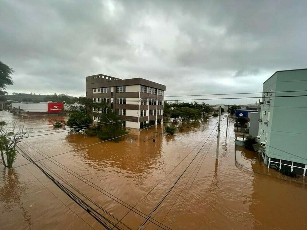 Aerial photo of a small town that’s flooded. The water reaches up close to the roof of the first floor of the buildings.
