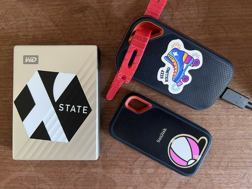 A photo of an external HDD and two external SSDs. They have stickers attached as per the main text.