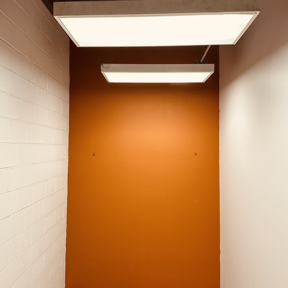 Orange wall with lights overhead and white walls on left and right.