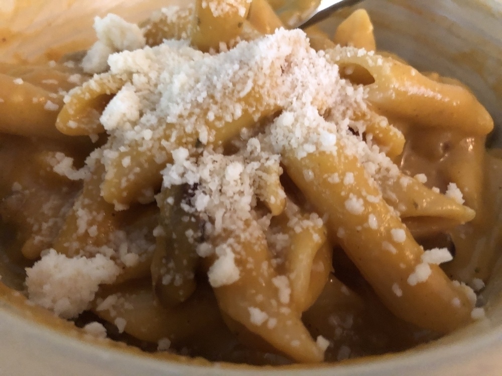 A butternut squash pasta with grated parmesan cheese in a yellow glazed bowl.