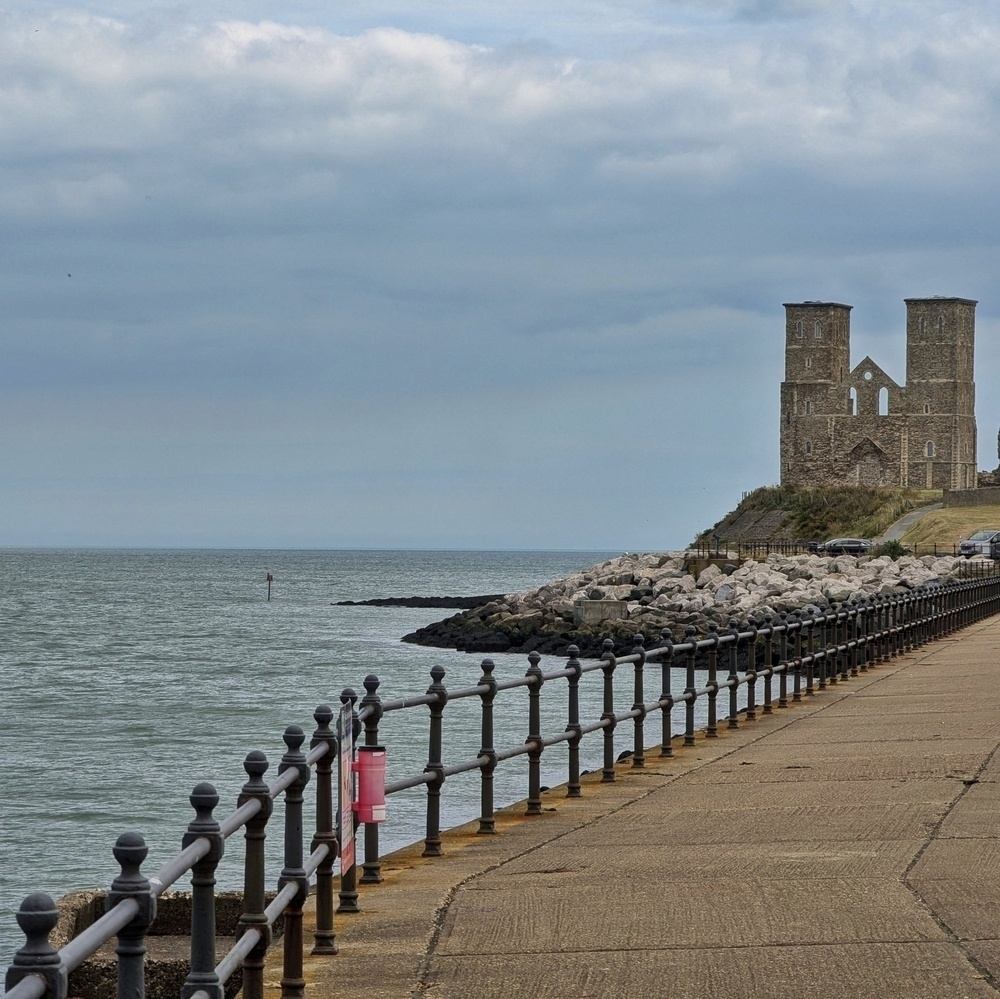 The waterfront path, flanked by a handrail, leads the way to the Reculver towers in north Kent