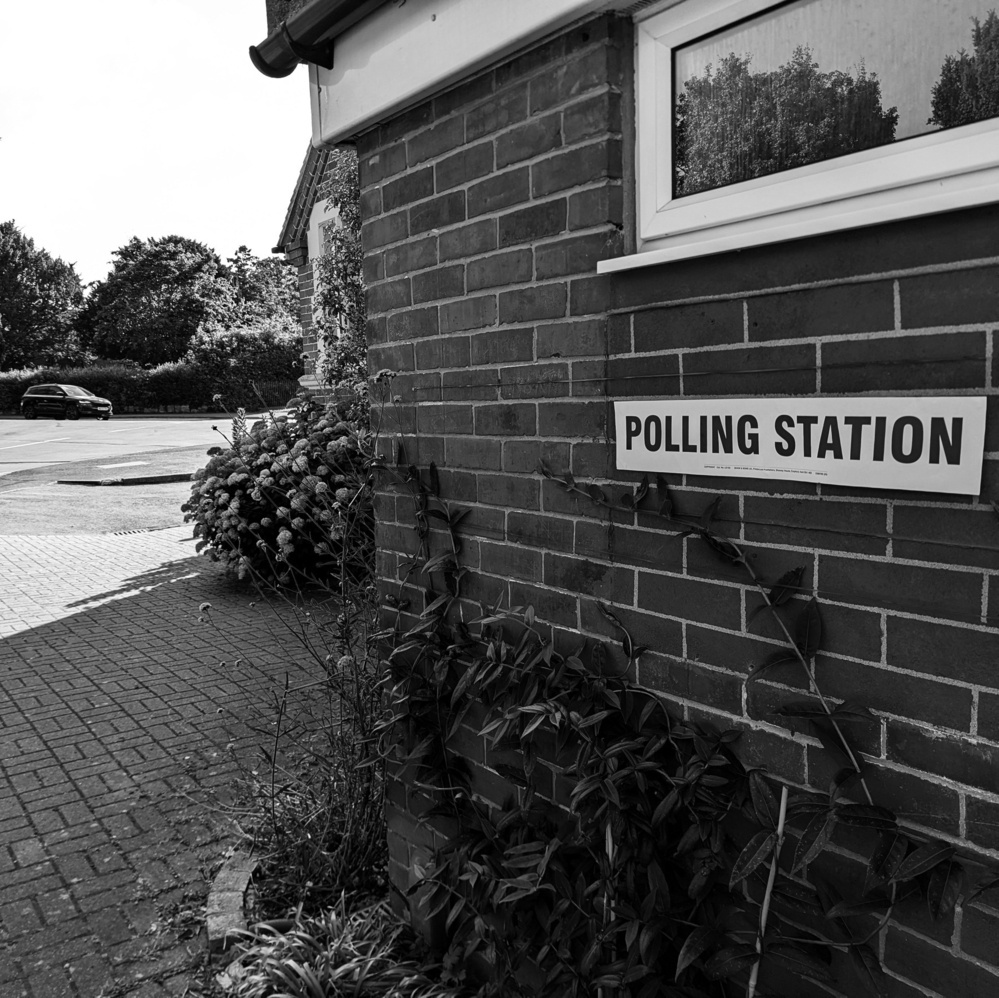 The outside of a UK polling station showing the “Polling Station” sign against a brick wall