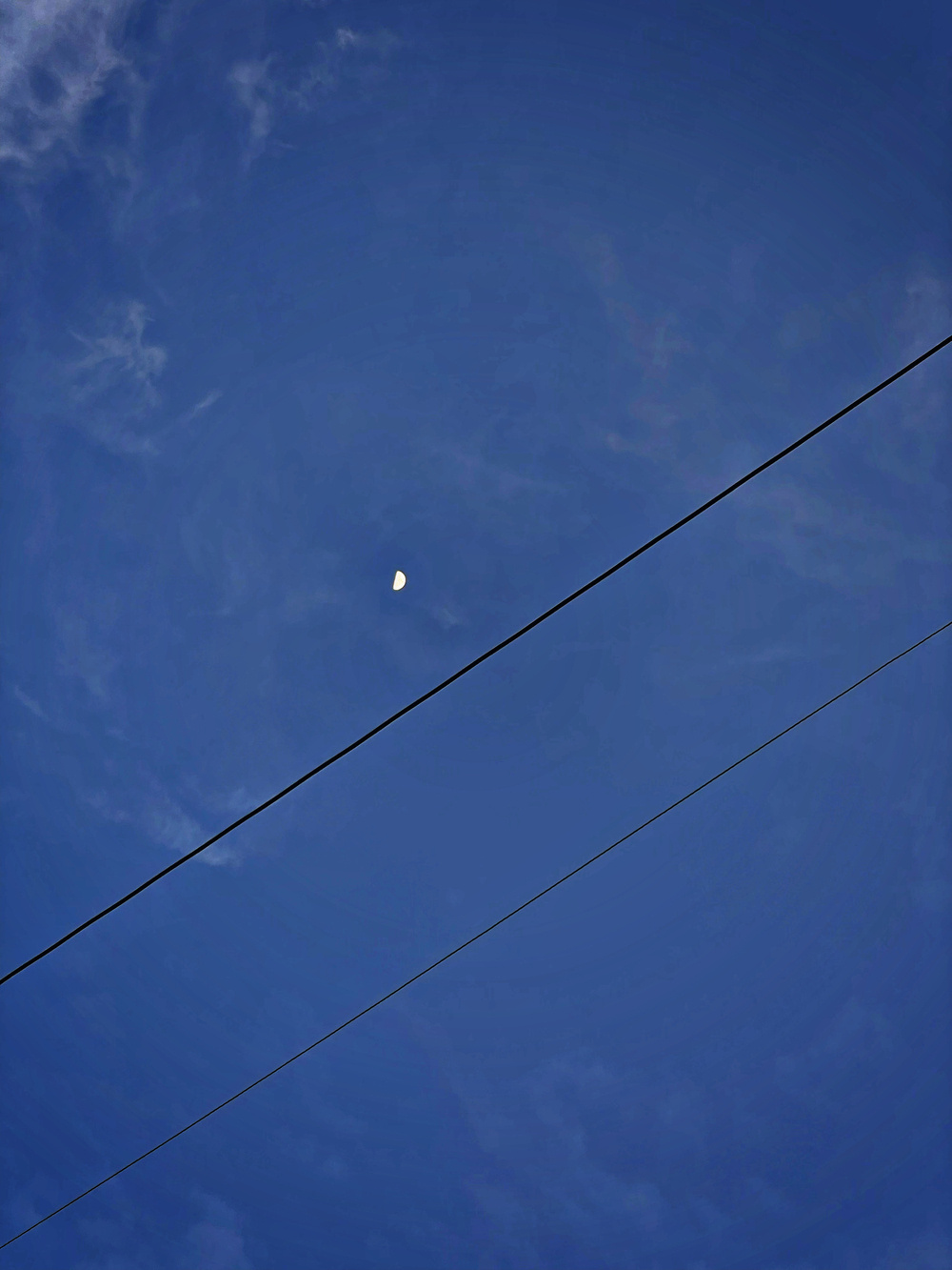 A half moon clearly visible over Manila amid clear skies