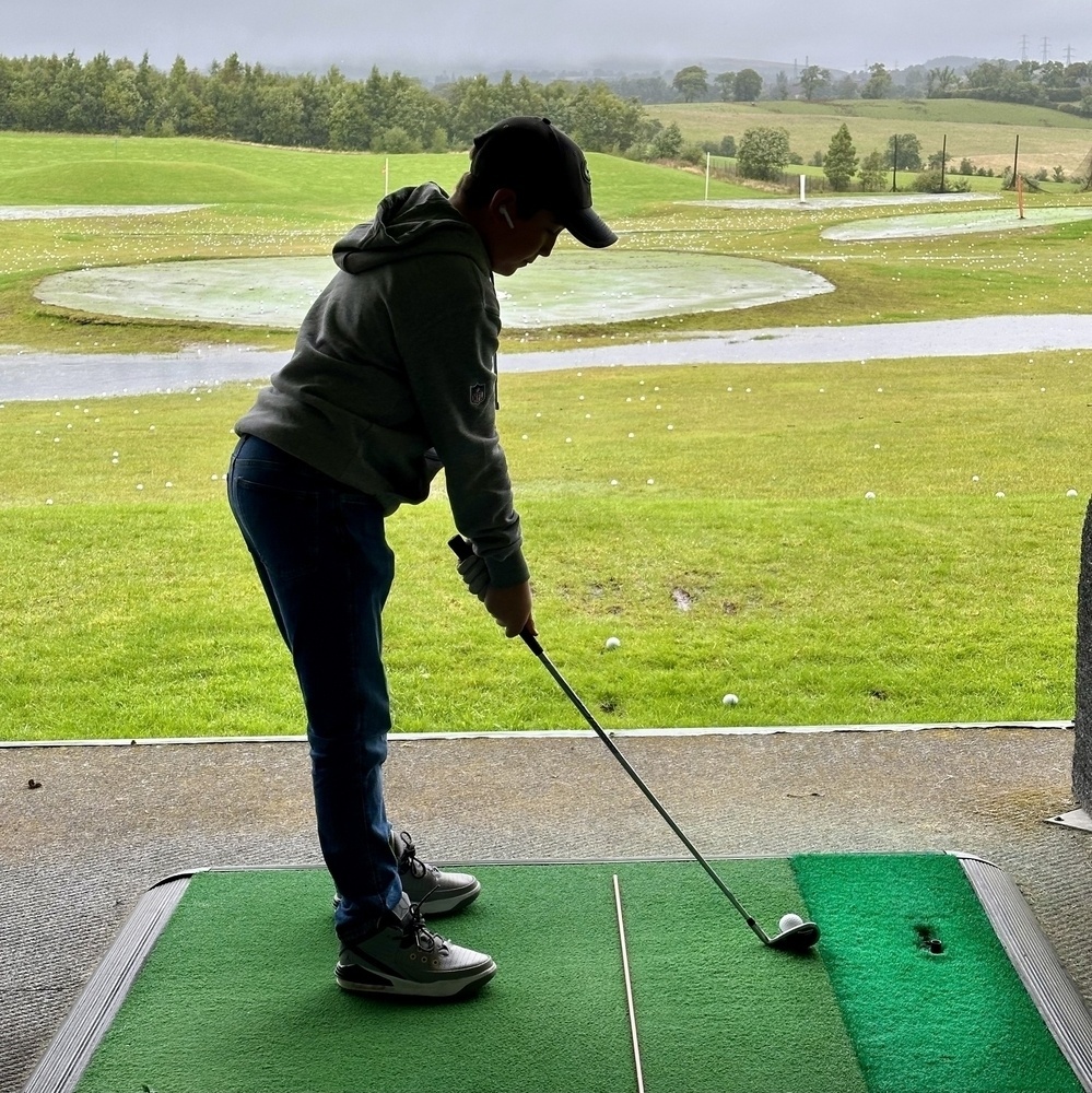 A person is practicing their golf swing on a driving range.