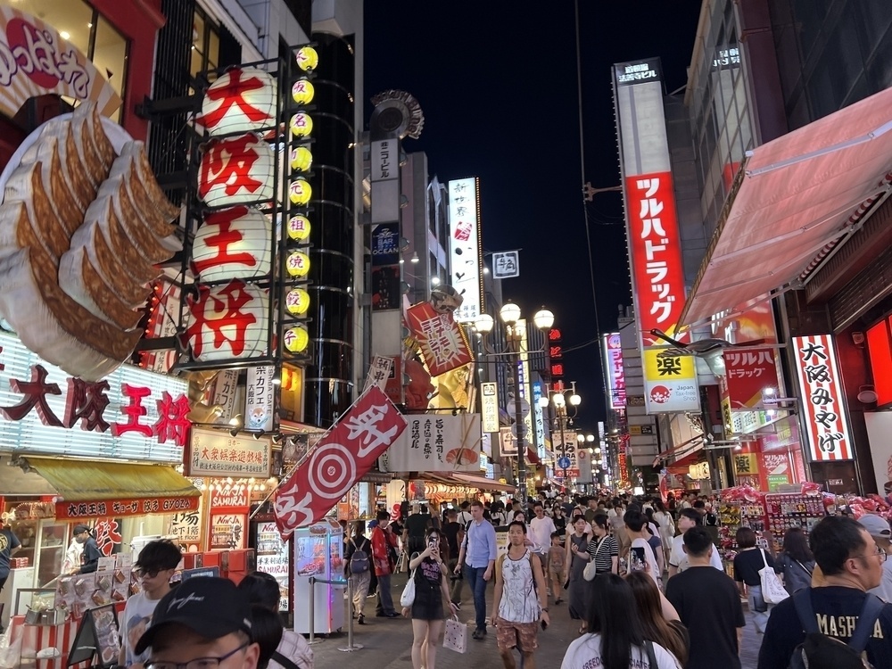Dotonbori Shopping street at night, crowded, with amazing 3D signage including a giant double serving of gyoza sticking out from one storefront