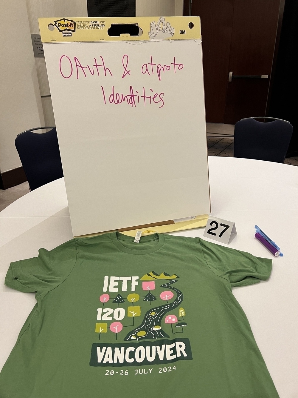 Tabletop easel with the words “OAuth & atproto identities”. On the table is a t-shirt commemorating IETF120 in Vancouver 