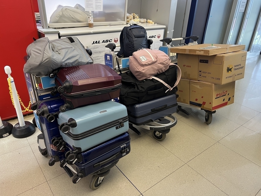 Three airport carts stacked with suitcases and boxes