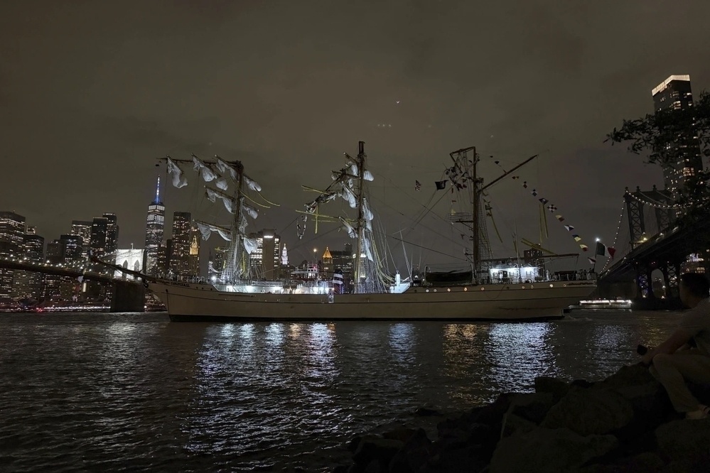 A tall ship, part of the training fleet for the Mexican Navy, is shown moored near the Brooklyn Bridge, all three of its masts snapped off near the top after colliding with the bridge.