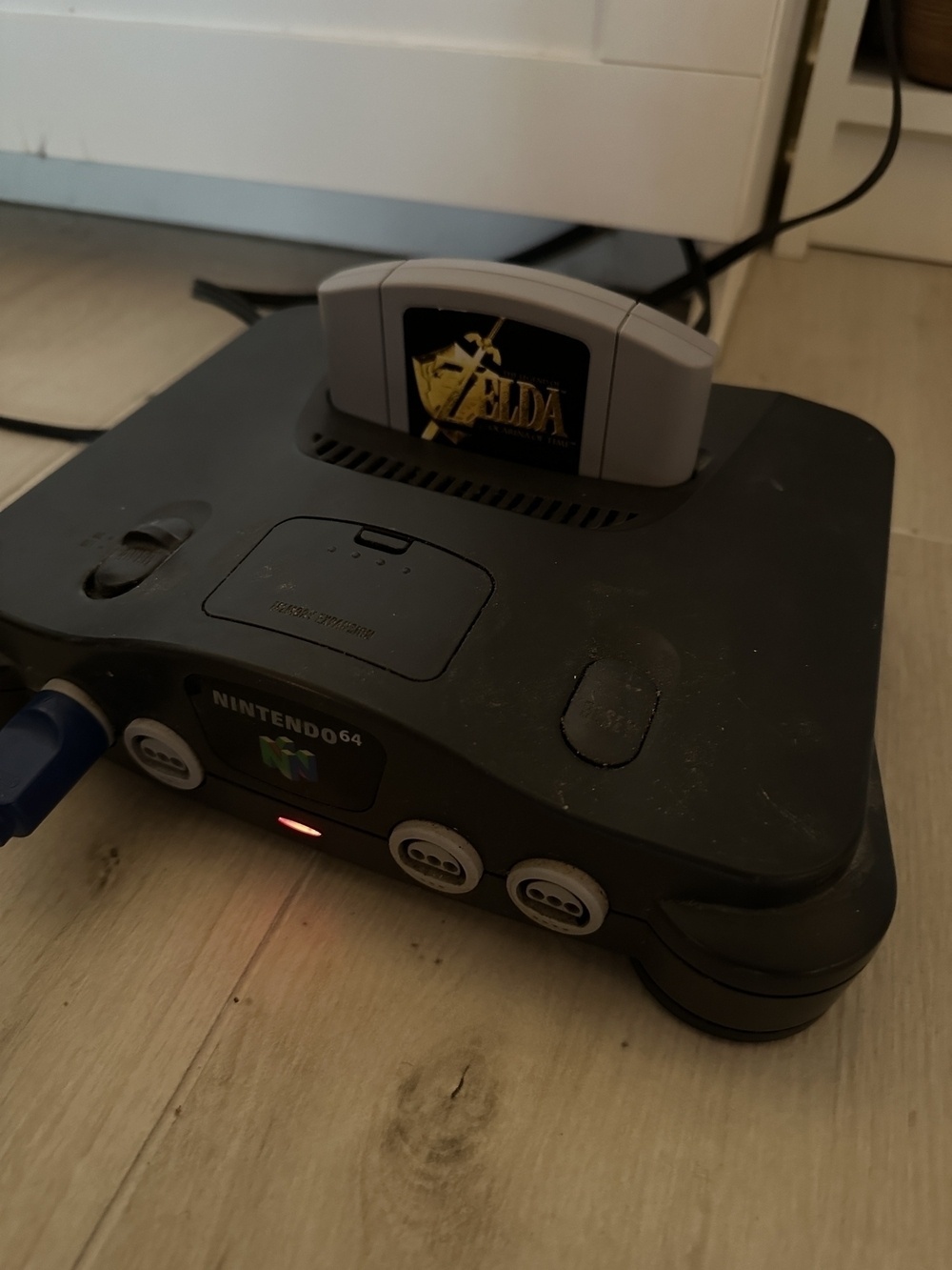 A Nintendo 64 console with a "Legend of Zelda" game cartridge inserted.