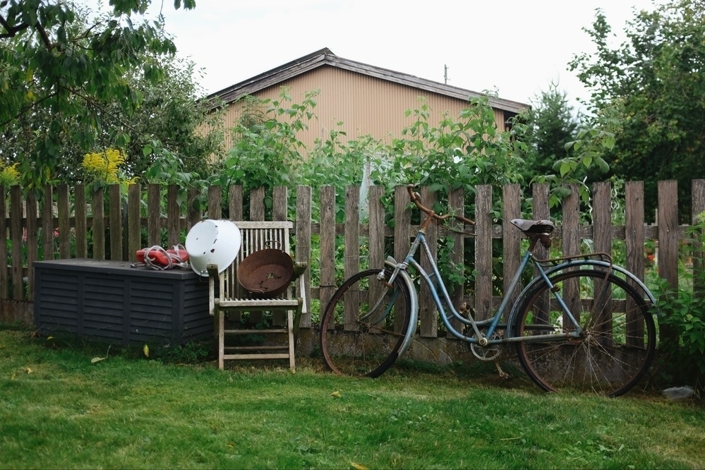 Fenced garden with decorative old bicycle, chair and pots