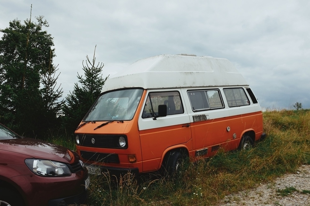 Classic orange and white Volkswagen Bulli camper parked on a meadow