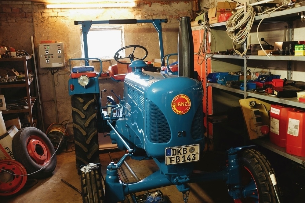 70 year old renovated Lanz tractor parked in a garage, sunlight coming in through a window in the background