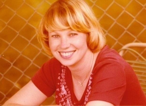 A woman with blonde hair and a beautiful smile wearing a red shirt