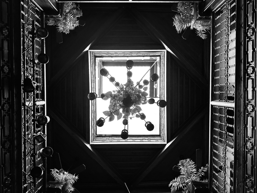 Looking up at a chandelier hanging below a skylight.