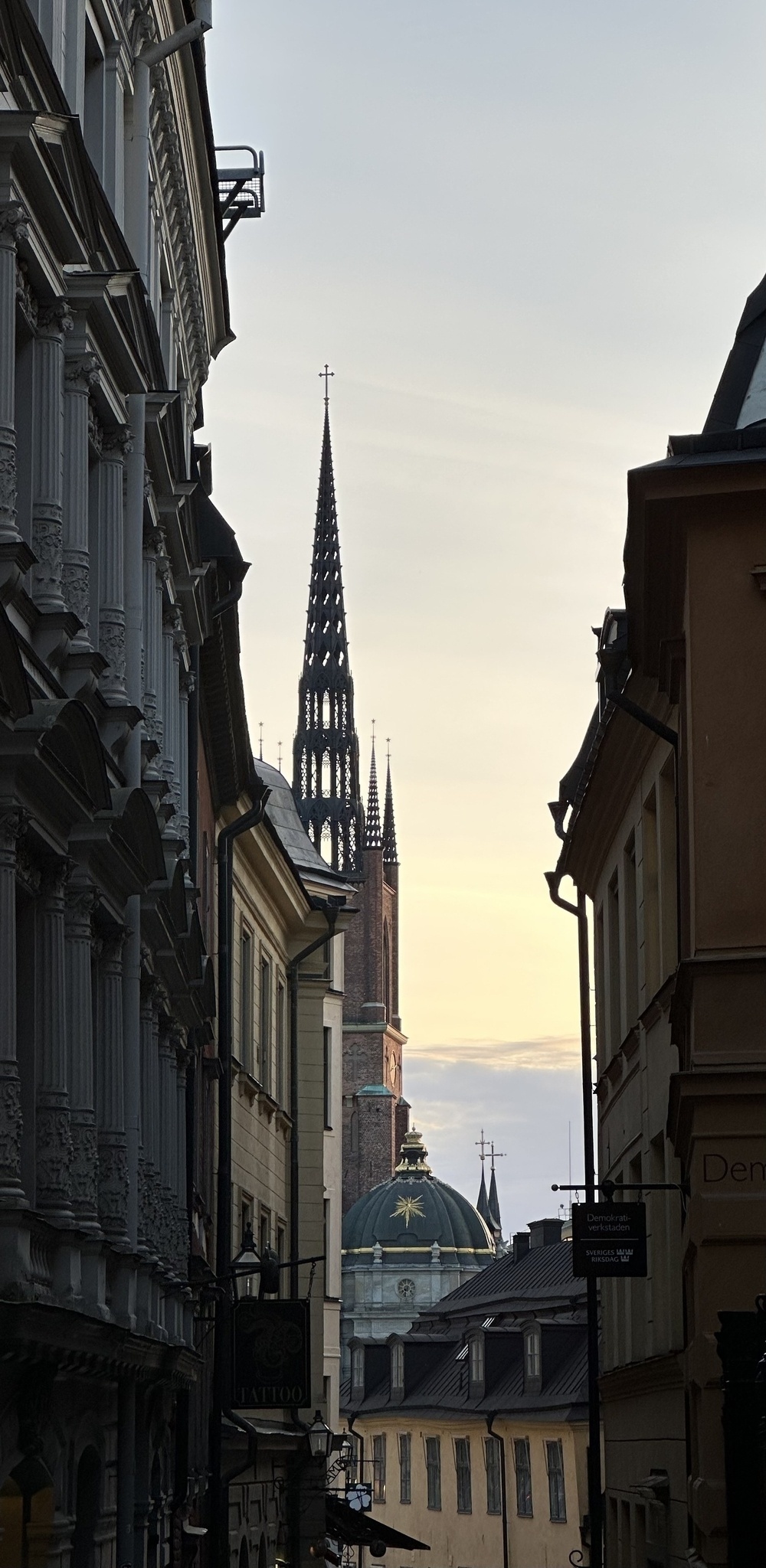 Looking down a dark narrow street towards an intricate spire.