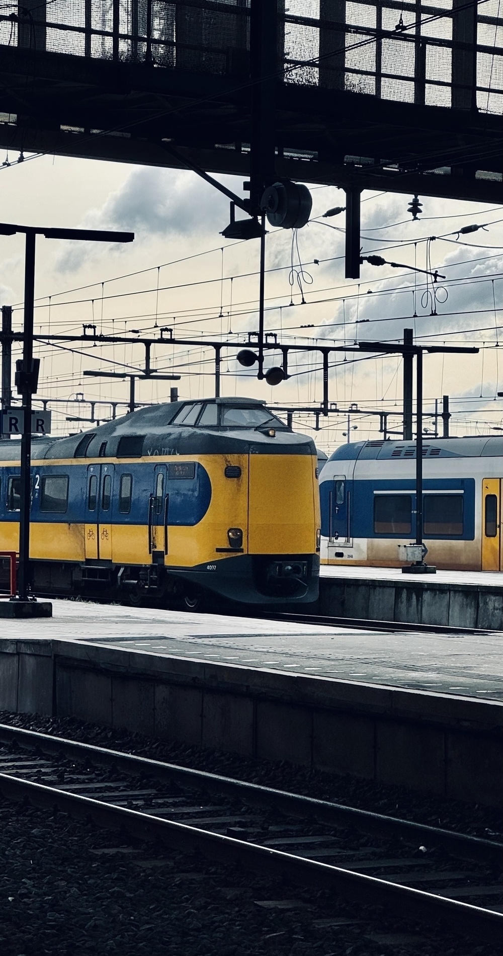 A train entering Amsterdam Centraal station, with lots of power lines above.