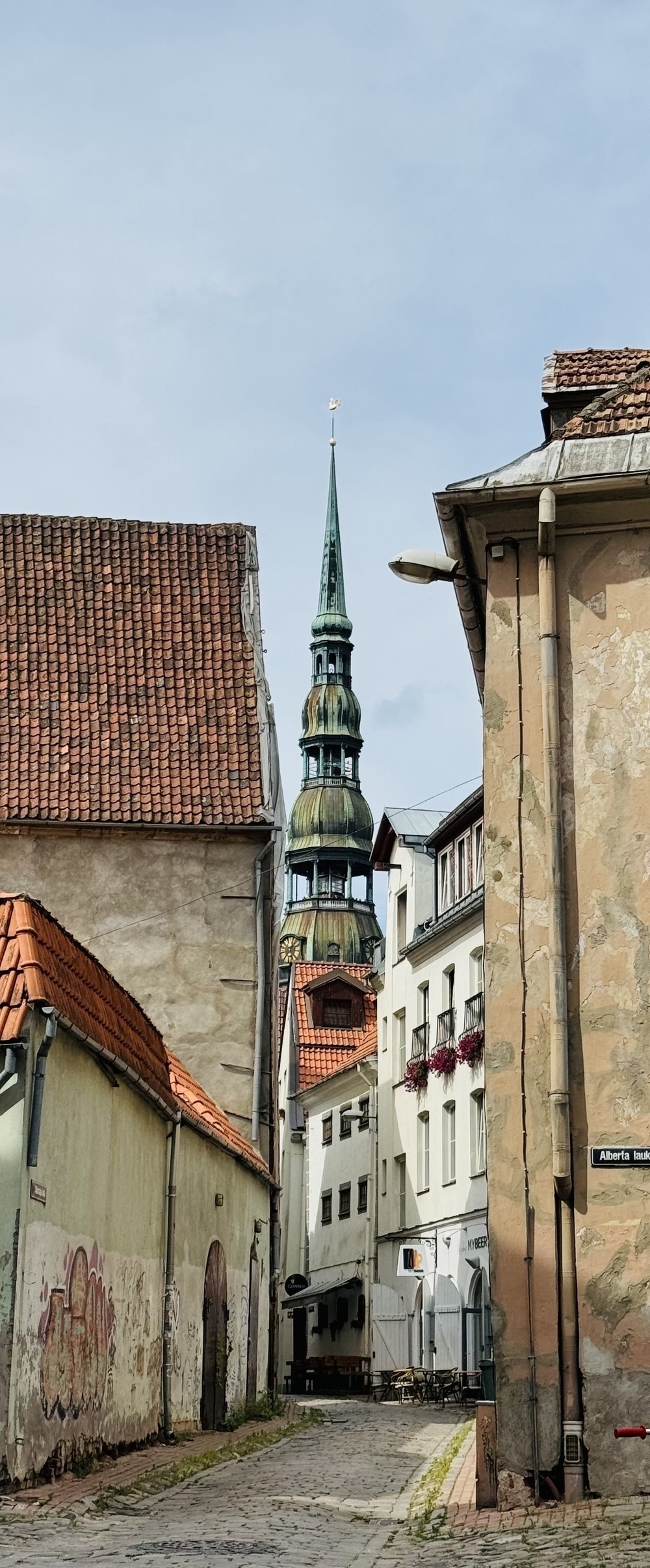 A multi-level spire rising above buildings around a narrow alley.