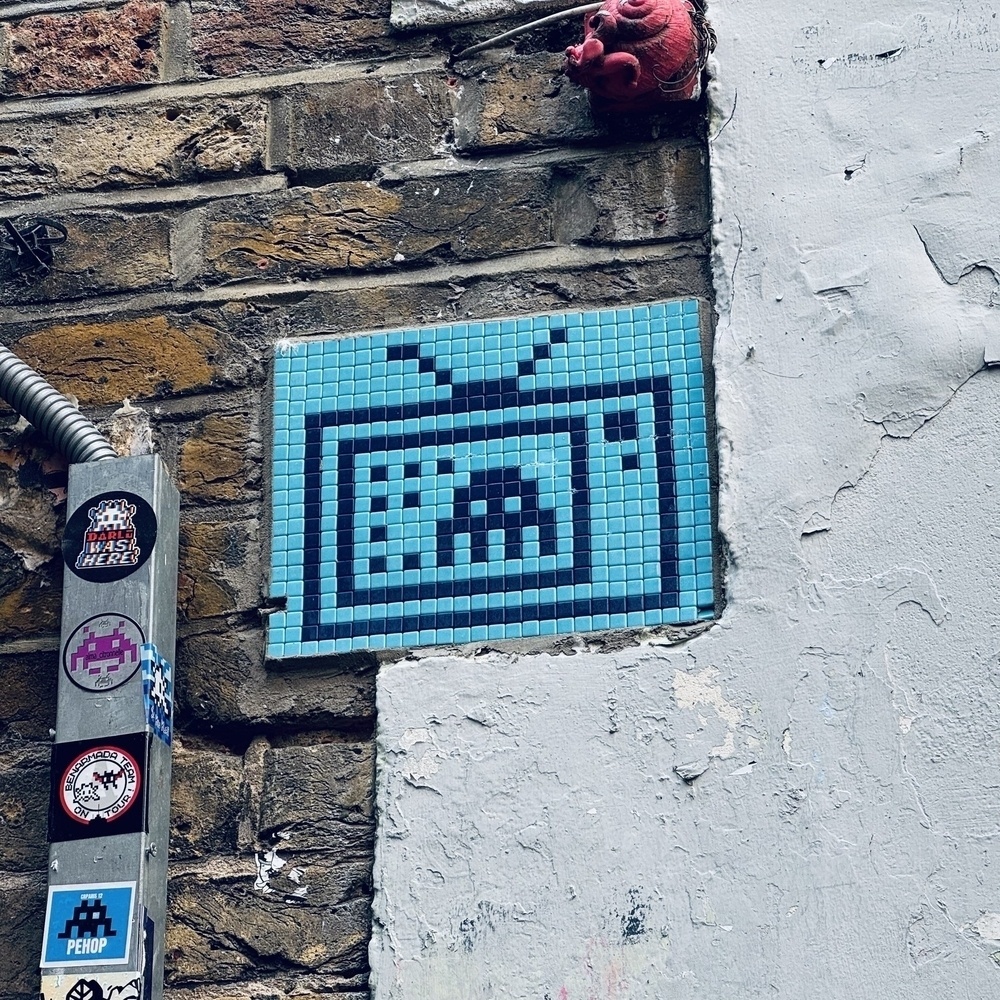 Tiled pixel art of a space invader on a TV, in light blue and dark blue.