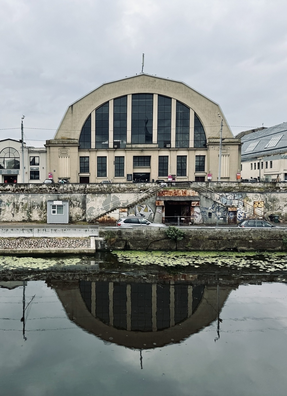 One of the rounded halls of Riga market reflected in water.