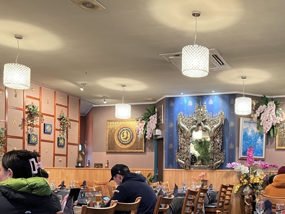 A view across tables to richly decorated walls with plenty of (artificial) flowers.