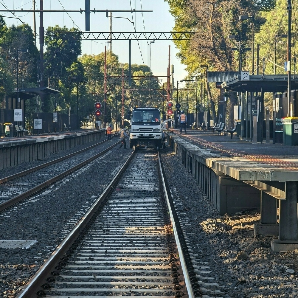 Truck on rail tracks at a station with workers.