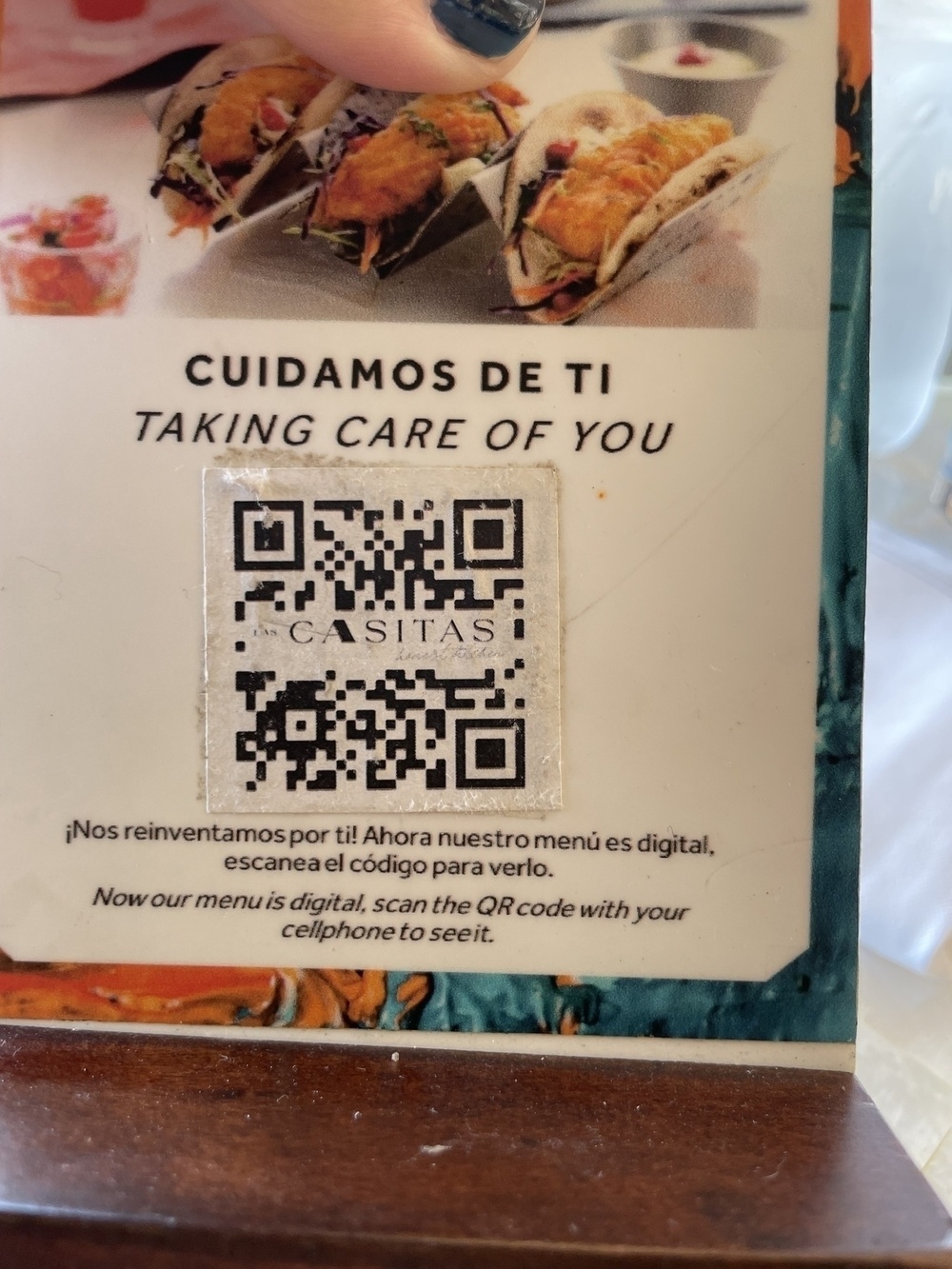 A Mexican food menu featuring tacos and a QR code on a wood table