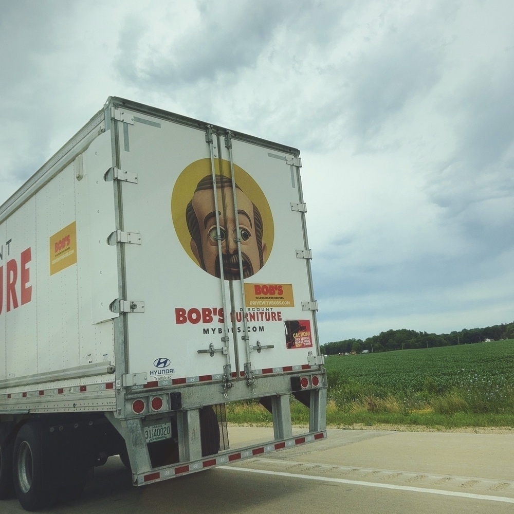 back of a semi truck trailer with an animated man with red text below Bob's Furniture