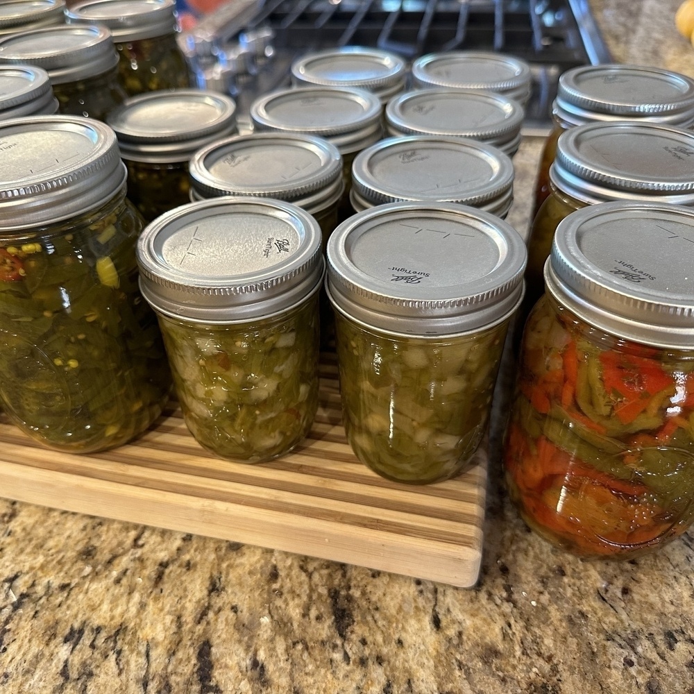 Various canned peppers on a wooden cutting board. 