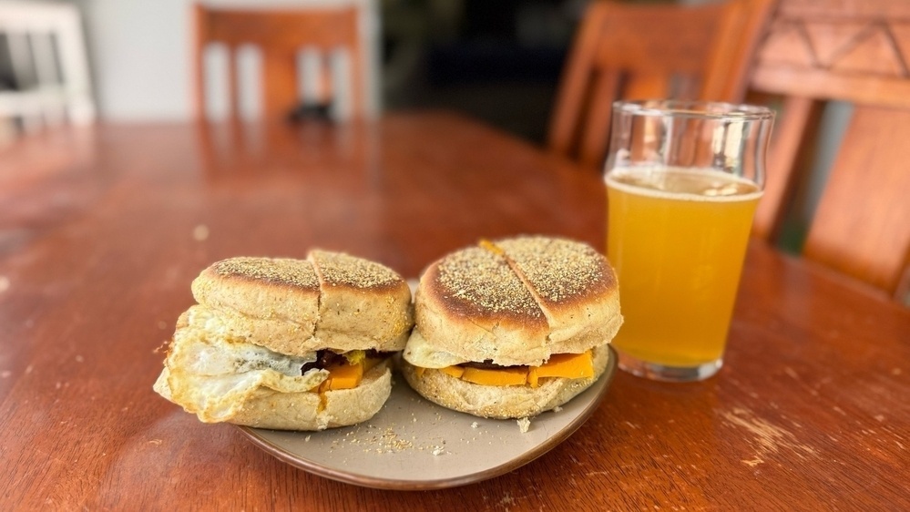 Two homemade sausage,egg, and cheese on English muffin sandwich's and a cold Hazy Jane from Brewdog. 