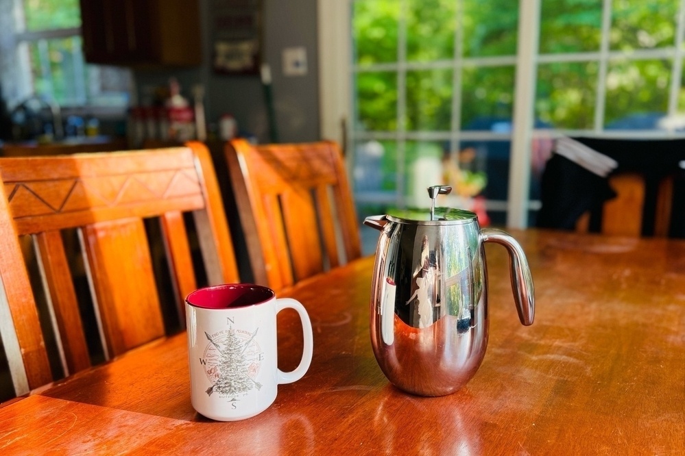 My favorite coffee mug, and a French press sing on our kitchen table in the sunlight on Sunday morning