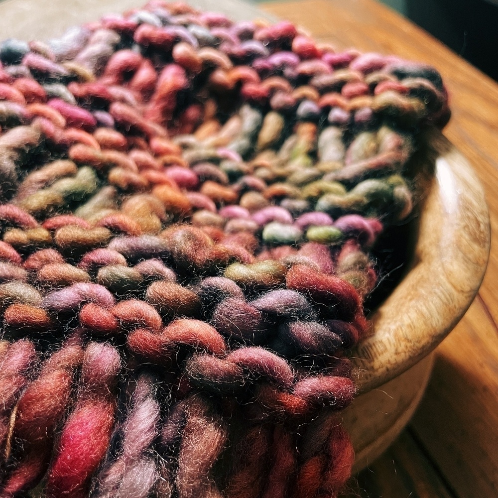 close-up of a piece of knitting with red, purple, and brown wool