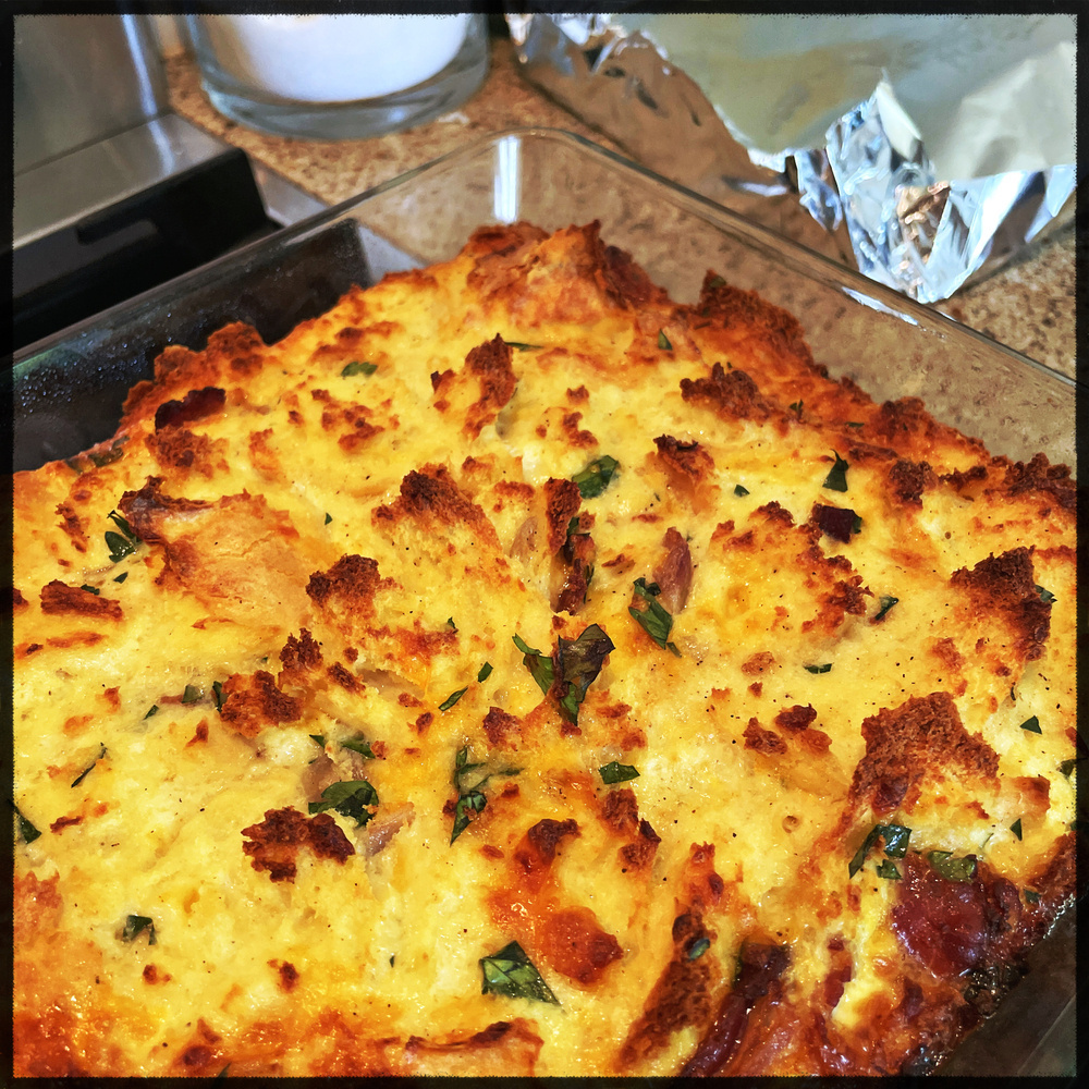 breakfast casserole with pieces of bacon, shallots, and parsley sprinkled throughout