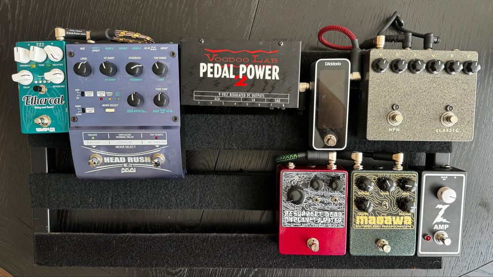 A pedalboard setup with various guitar effects pedals including: Wampler Ethereal (Delay and Reverb), Akai Headrush (Looper/Delay), Voodoo Lab Pedal Power 2 (Power Supply), D’Addario Chromatic Tuner.