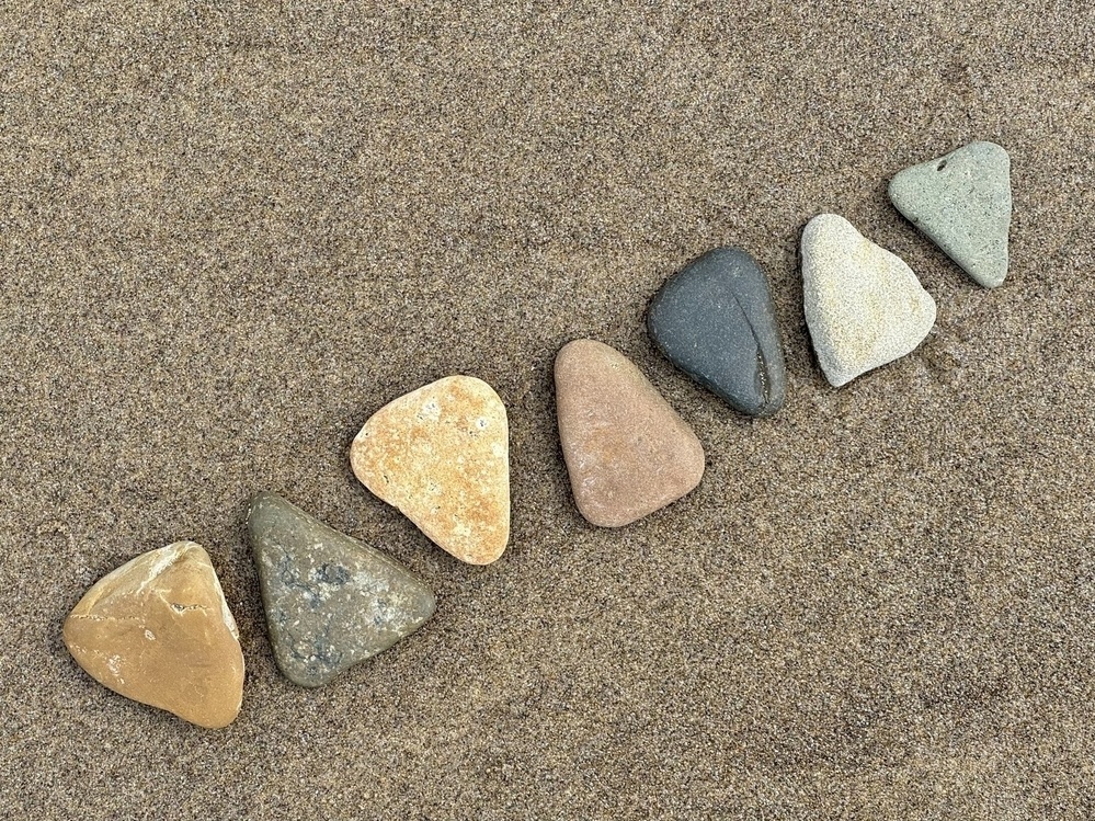 Seven triangle shaped rocks on the sand. 