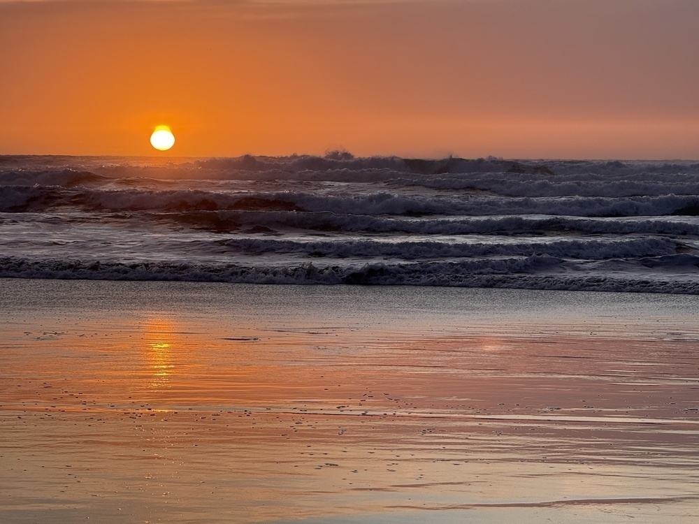 Orange sunset on choppy surf.