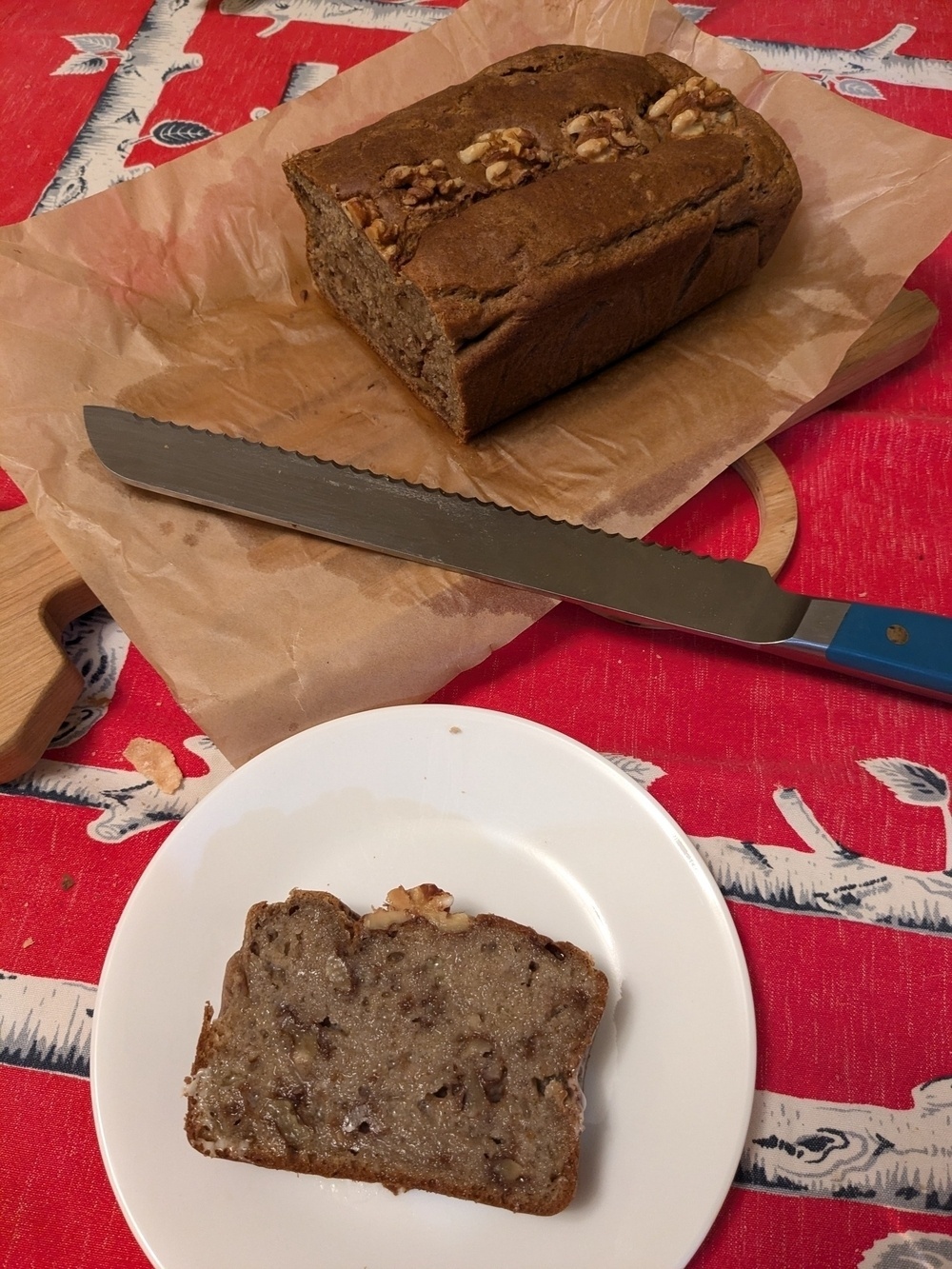 slice of banana bread next to a loaf with walnuts on top