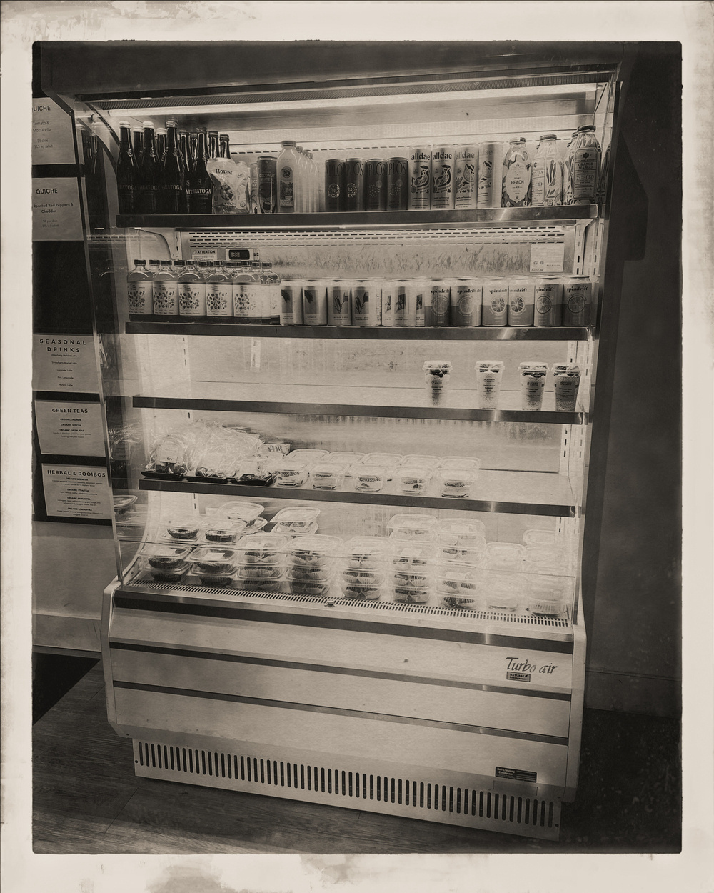 Refrigerated drinks case in shop. Vintage black and white filter applied.