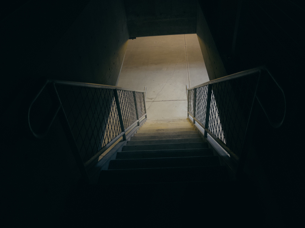 Stairway to parking garage below, illuminated by lighting from the parking garage.