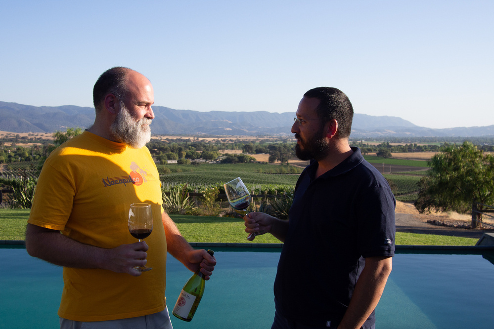 Two man share wine by a pool and vineyards - Olympus E-M5
