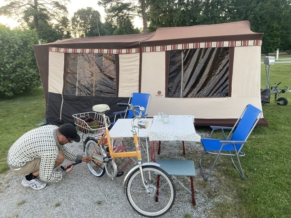 Combi-Camp bak (familiemodellen fra 1985), campingbord av ymse datoer, fyr i islender pumper opp dekk på en gul Kombi Indus. 