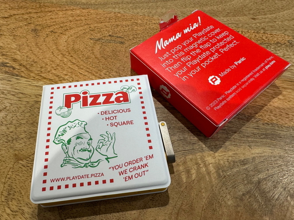 The image shows a small, square, white play date cover designed to look like a pizza box, featuring the text “Pizza” and an illustration of a chef making an “okay” hand gesture. The phrases “Delicious,” “Hot,” and “Square” appear on the packaging 