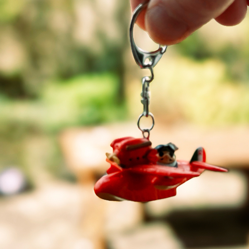 A red plane toy keyring being held by a finger