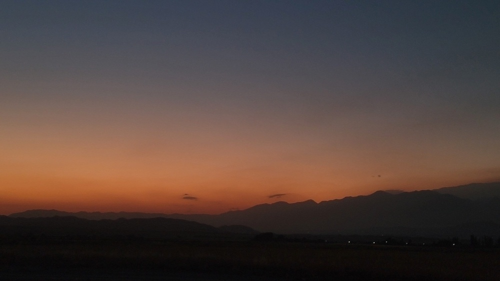 dawn sky before sunrise - dark blue/gray sky with a dark orange horizon over mountains 