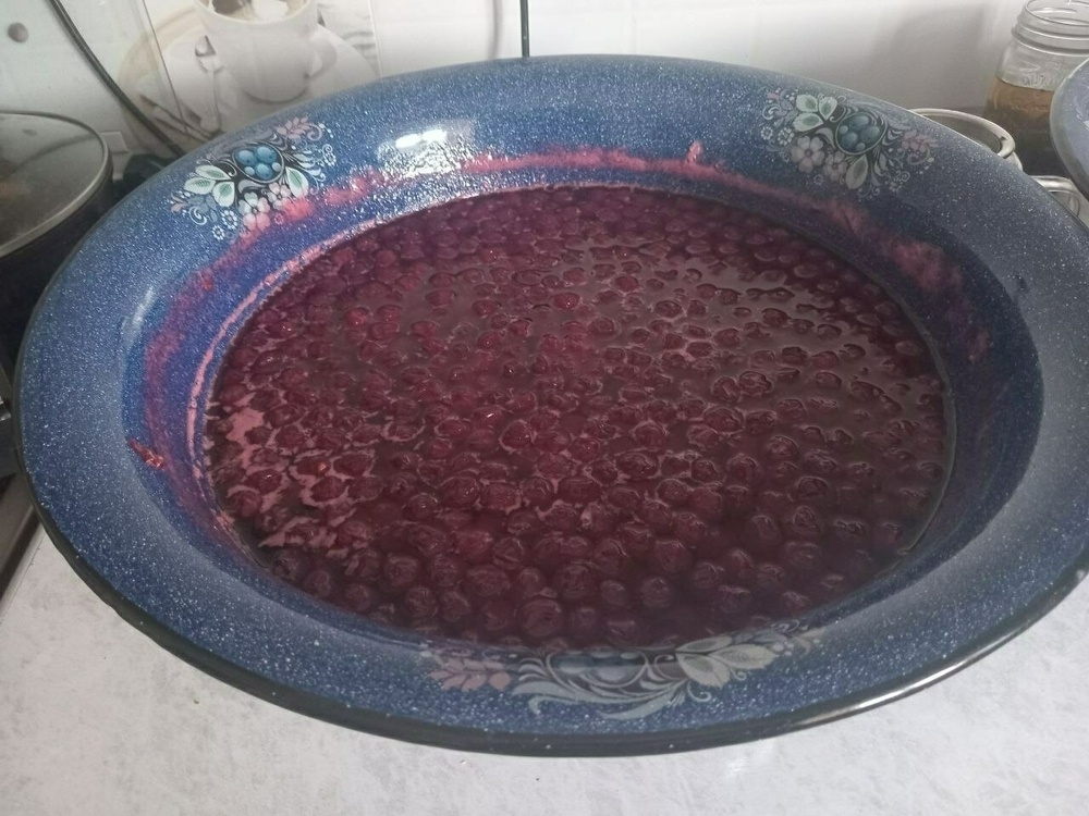 large blue bowl of cherry jam, including whole cherries
